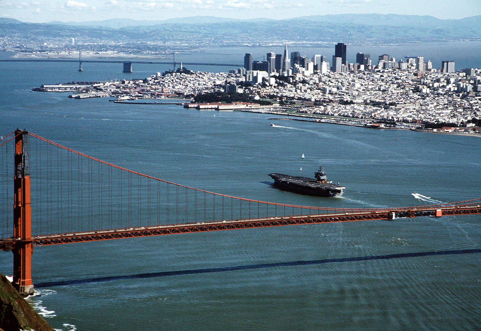 Harbor rules help traffic move smoothly and predictably. Description: Aerial photo of Golden Gate Bridge and San Francisco skyline with aircraft carrier USS Enterprise having just passed under the bridge entering the harbor.